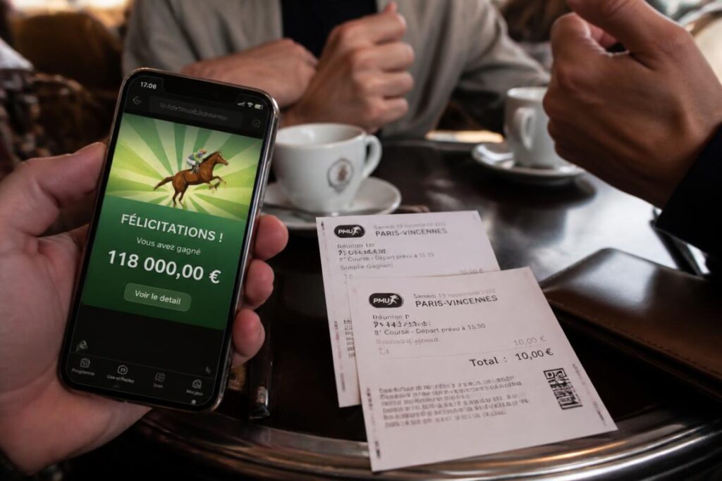 Ticket de paris hippiques gagnant sur table de bistrot avec smartphone notif 118 000 euros